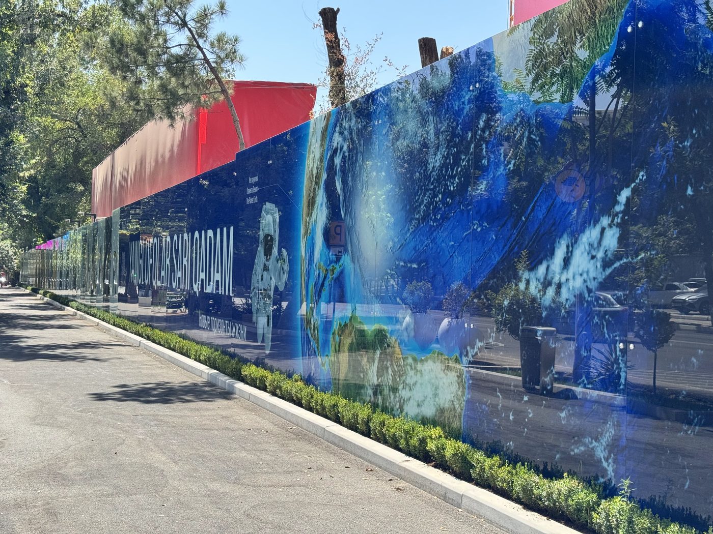 Space-themed artwork printed across glass hoarding panels in Tashkent